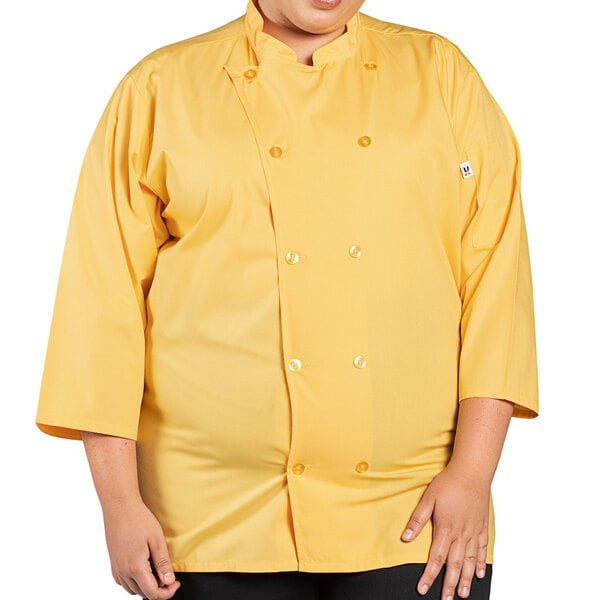 A woman wearing a yellow Uncommon Chef 3/4 length sleeve chef coat.