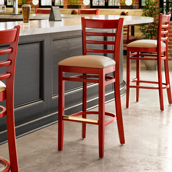 A mahogany wood bar stool with light brown vinyl seats.