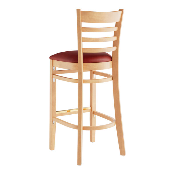 A Lancaster Table & Seating wooden bar stool with a burgundy vinyl seat.