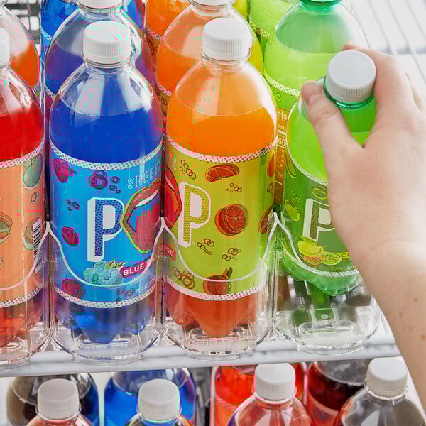 A hand using a white 8 Lane Universal Pusher Glide to organize a green plastic bottle in a refrigerator.