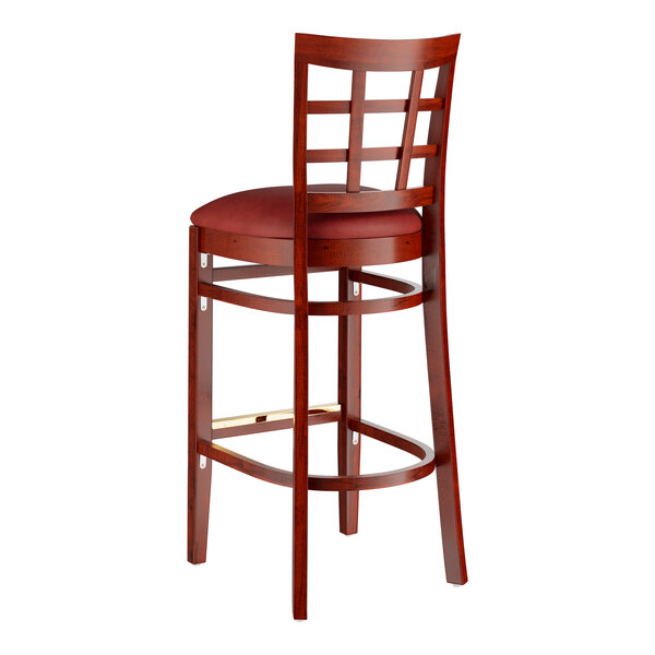 A Lancaster Table & Seating wooden bar stool with a burgundy cushion.