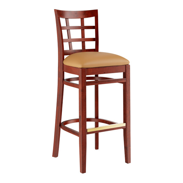 A Lancaster Table & Seating mahogany wood bar stool with a light brown vinyl seat.