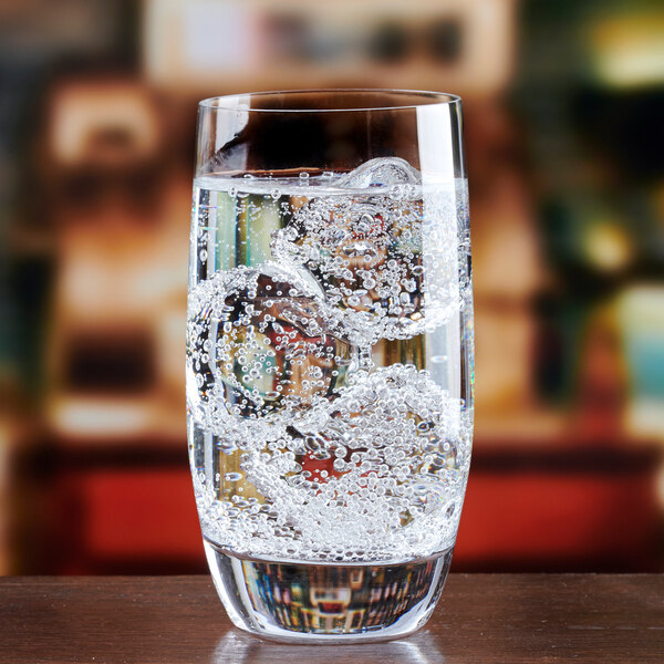 A clear highball glass filled with sparkling water and ice.