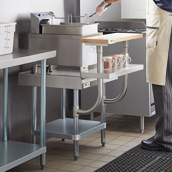 A man using a Regency stainless steel equipment stand in a kitchen.