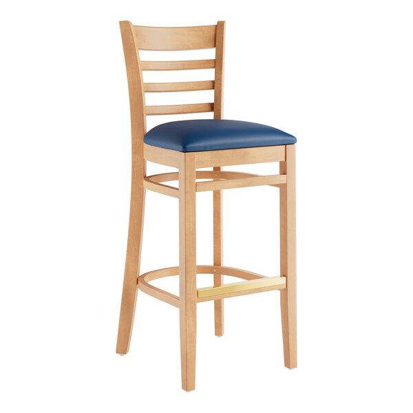 A Lancaster Table & Seating wooden bar stool with a navy blue cushion on the seat.
