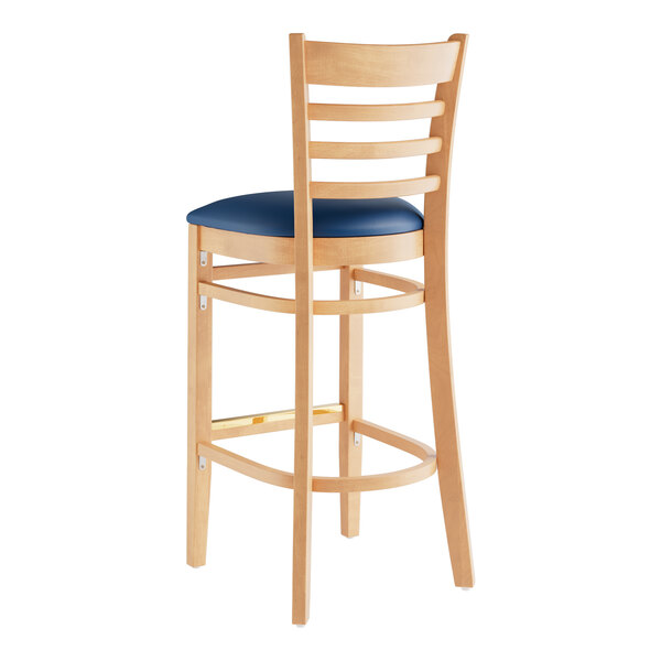 A Lancaster Table & Seating wood ladder back bar stool with navy vinyl seat on a wooden chair with a blue cushion.