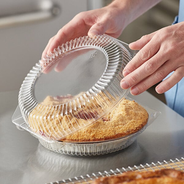 A person holding a Choice clear plastic container with pie inside.