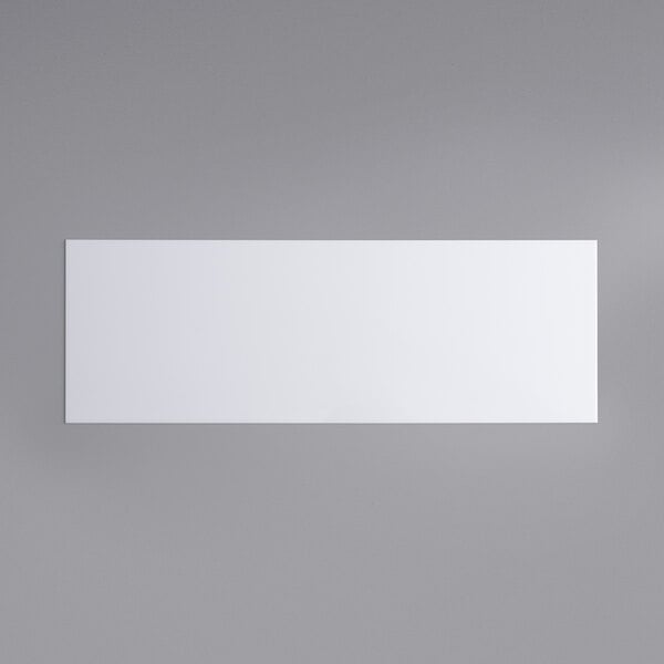 A white rectangular object on a grey surface.