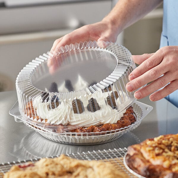 A person putting a pie into a Choice clear plastic pie container.