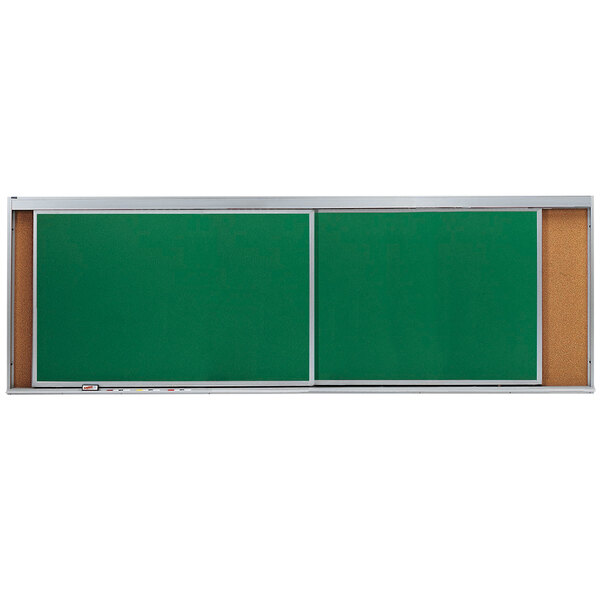 A green cork board with two horizontal sliding white boards on it.