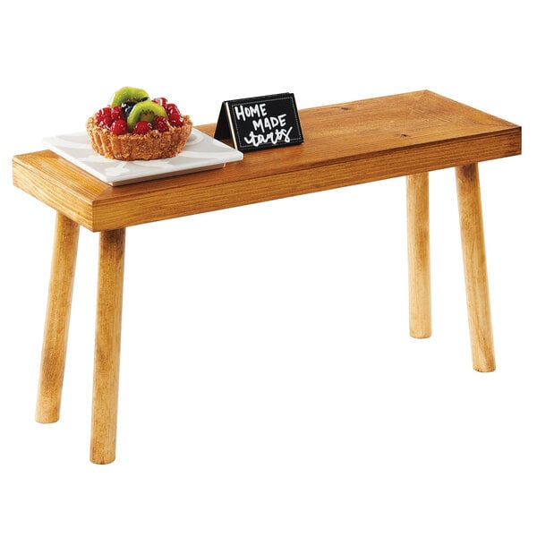 A table with a Cal-Mil Madera rustic pine wood riser holding a plate of fruit.