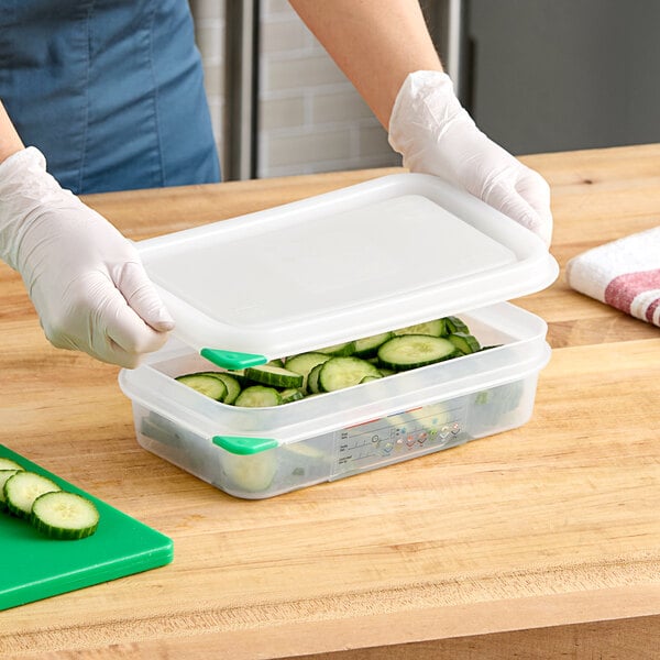 A person in gloves holding a white Araven plastic container with cucumbers in it.