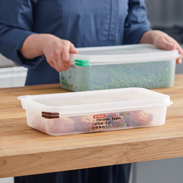 A woman holding an Araven translucent plastic container with chicken in it.