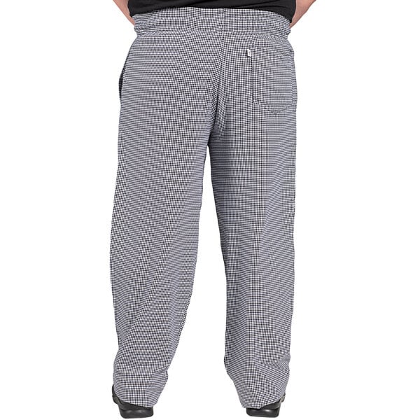 Uncommon Chef 4000 unisex houndstooth chef pants with a pocket, worn by a person in black and white checkered pants.