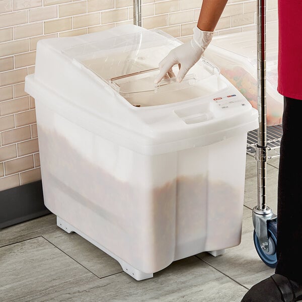 A person in gloves using an Araven ingredient bin with a sliding lid to put food in.