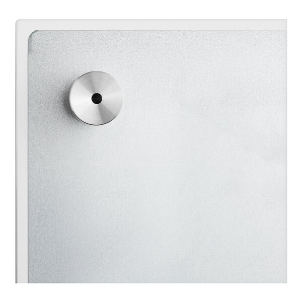 A silver Quartet magnetic glass dry erase board with a black hole in the middle on a white wall.
