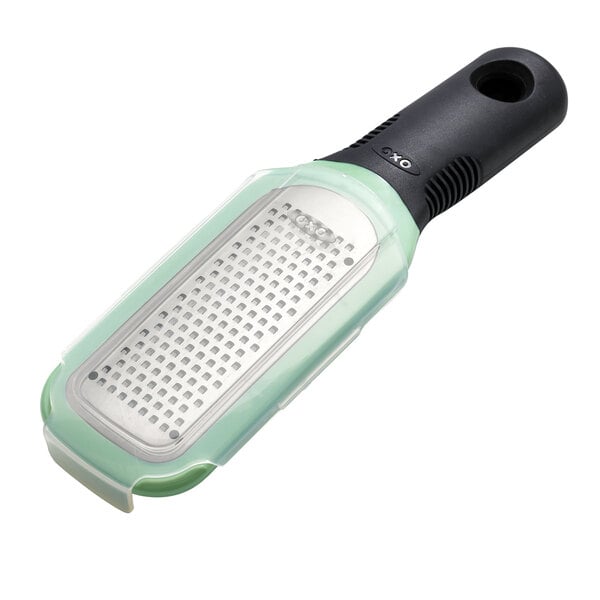 An OXO stainless steel grater with a green non-slip handle.