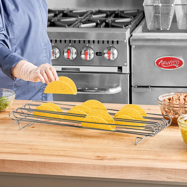 A woman placing tortillas in a Tablecraft taco rack on a table.