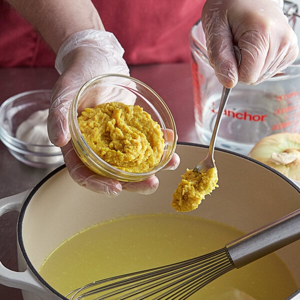 A person mixing Knorr Chicken Base in a glass bowl.