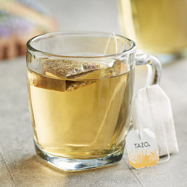 A glass mug of Tazo Calm Chamomile Tea with a tea bag in it.