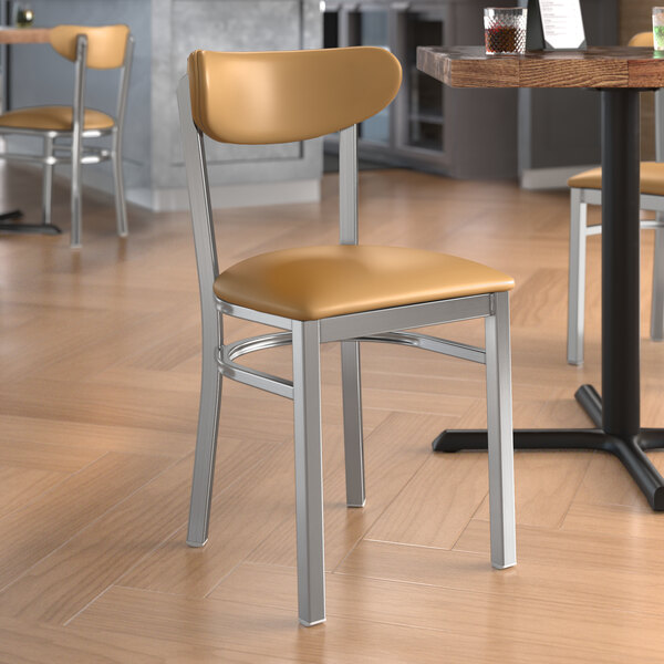 A Lancaster Table & Seating clear coat finish chair with light brown vinyl seat and back in a restaurant.