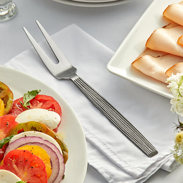 A plate of food with an American Metalcraft wavy aged stainless steel cold meat fork on a table.