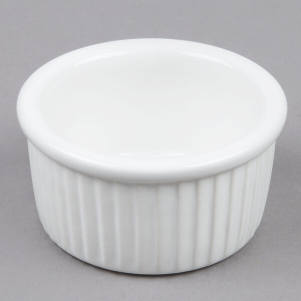 A Tuxton white fluted ceramic ramekin on a gray surface.