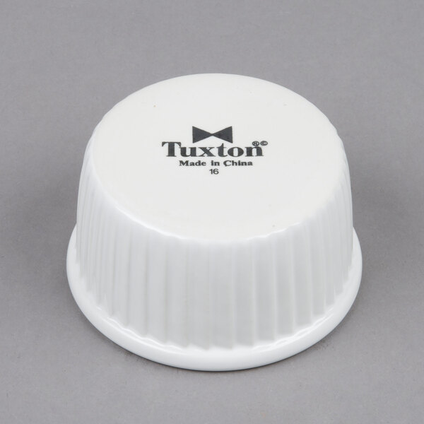 A white plastic lid with black text that reads "Tuxton" for a Tuxton white china ramekin.