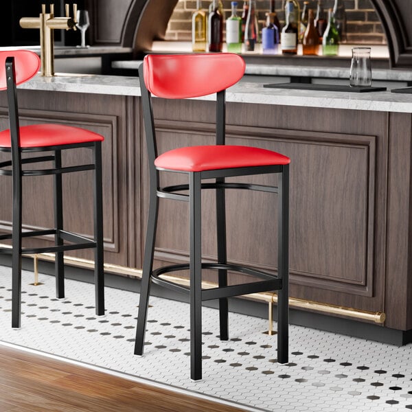 A black bar stool with a red vinyl seat and backrest.