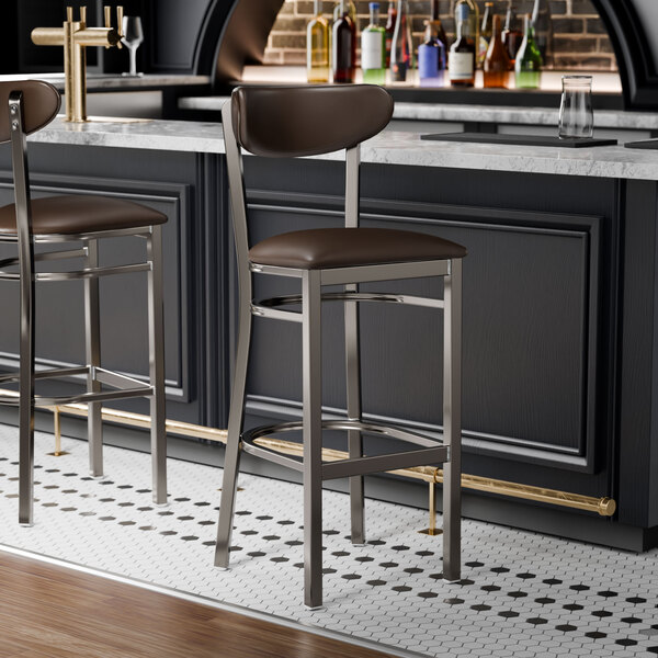 Two Lancaster Table & Seating Boomerang bar stools with brown vinyl seats and backs at a bar counter.