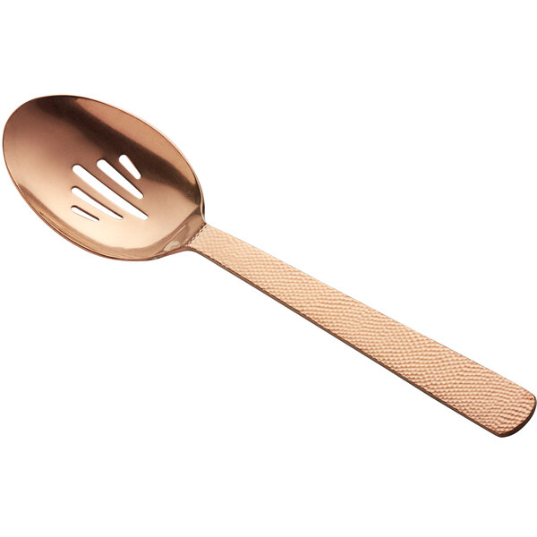 A close-up of an American Metalcraft hammered bronze slotted serving spoon with a rose gold handle.