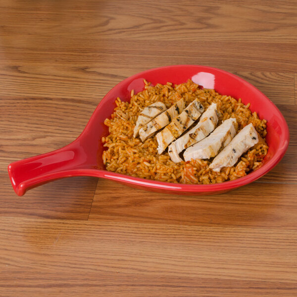 A CAC red spoon shaped bowl with rice and chicken on a plate.