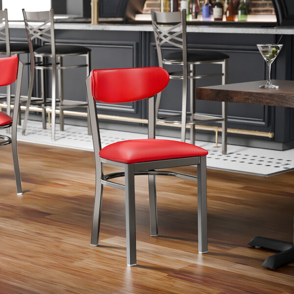 A metal chair with a clear coat finish featuring a red vinyl seat and backrest.