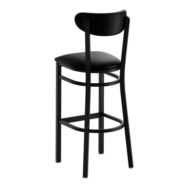 A black bar stool with a black vinyl seat and backrest, featuring a metal frame and footrest.