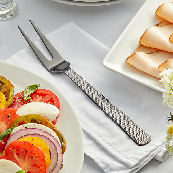 A plate of food on a table with a black vintage cold meat fork next to it.