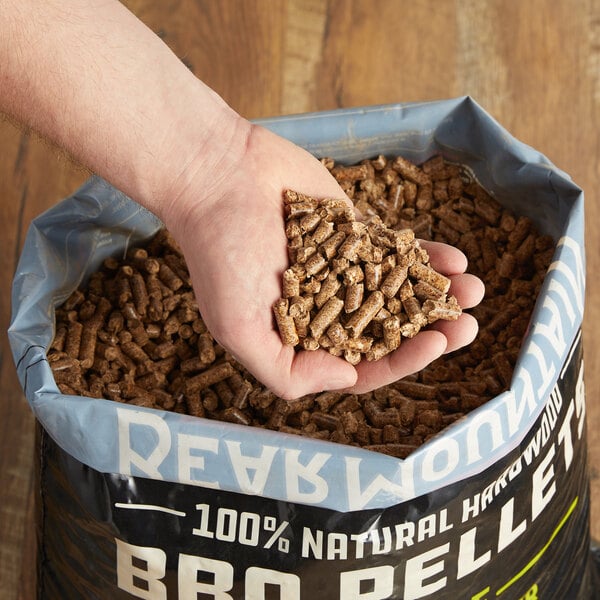 Person grabbing a handful of wood pellets out of a bag