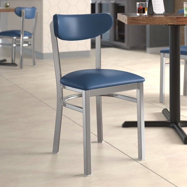 A Lancaster Table & Seating chair with a navy vinyl seat and back at a table in a restaurant.