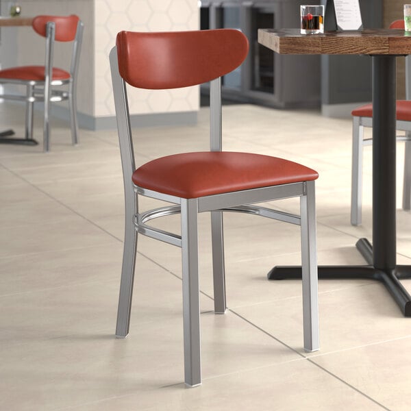 A Lancaster Table & Seating chair with a burgundy vinyl seat and back on a table in a restaurant.