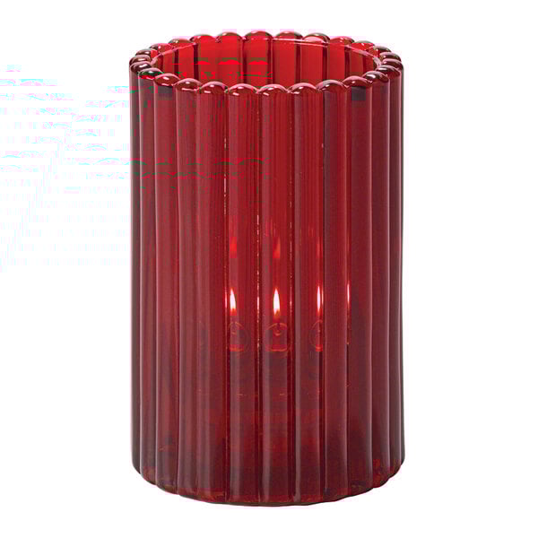 A Hollowick Ruby glass candle holder with a lit red candle in it.