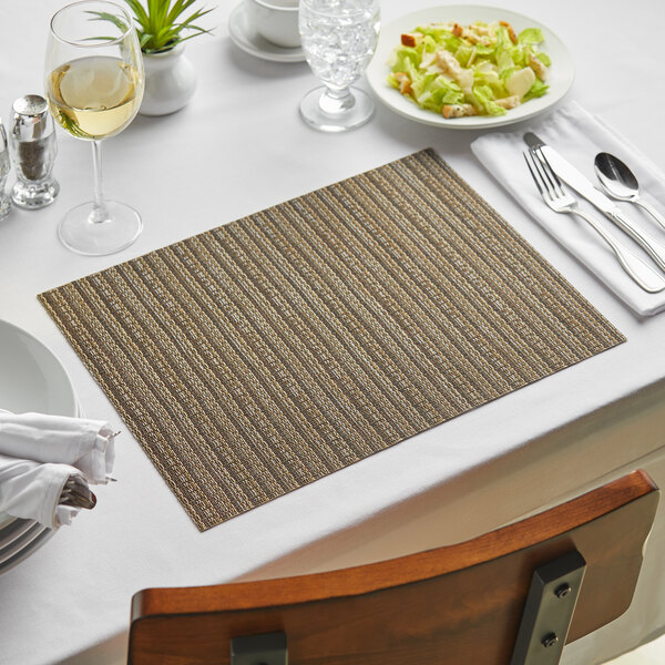 A table set with a Mocha Urban Woven Vinyl rectangle placemat with a plate of salad and wine glasses.