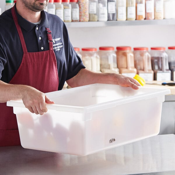 A man in an apron holding a white plastic Vigor food storage box.