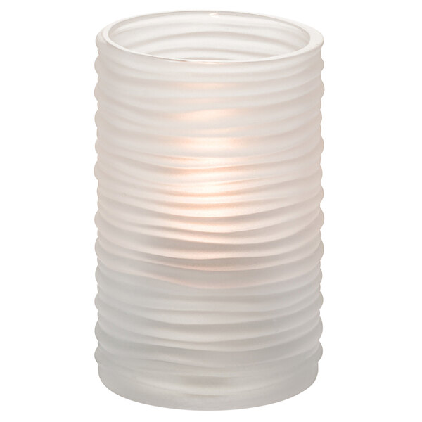 A clear glass cylinder candle holder with a lit white candle inside.