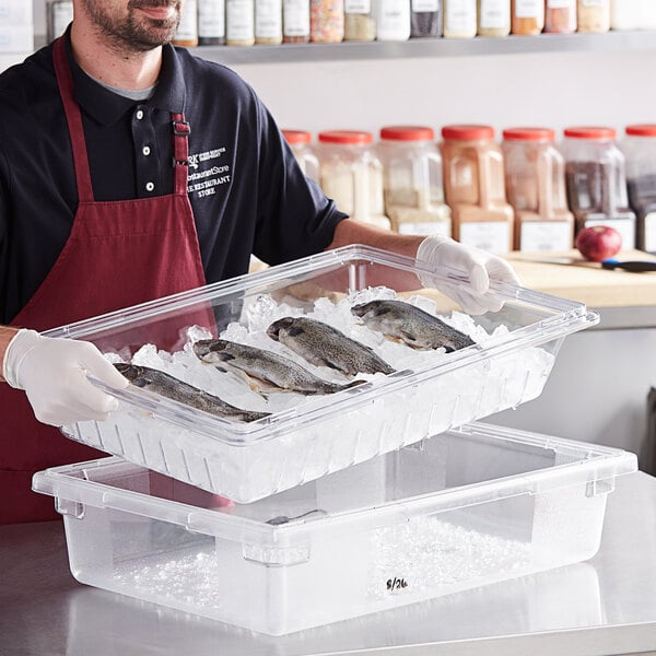 A man holding a clear Vigor food container filled with fish.