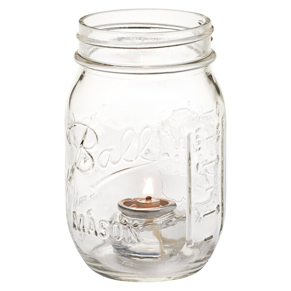 A Hollowick Firefly clear glass jar with a lit candle inside.