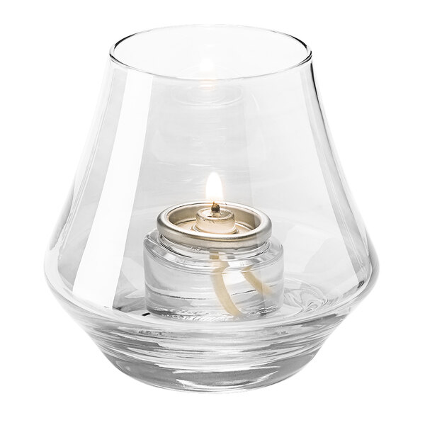 A Hollowick clear glass votive candle holder with a lit candle inside.