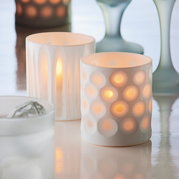 A close-up of a white porcelain Hollowick candle holder with white dots.