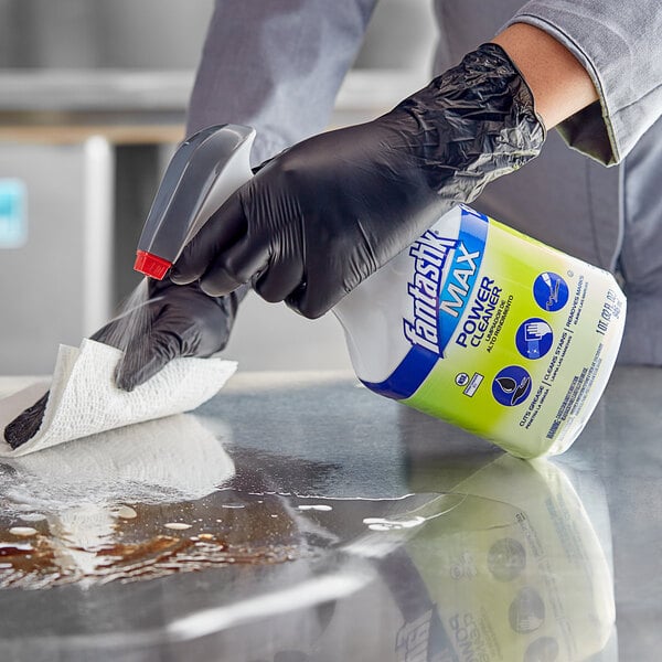 A person in black gloves using SC Johnson fantastik Max Power All-Purpose Cleaner to clean a counter.