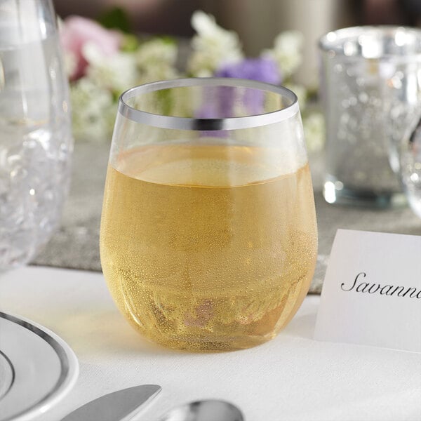 A clear plastic stemless wine glass with a silver rim, filled with a light-colored beverage.