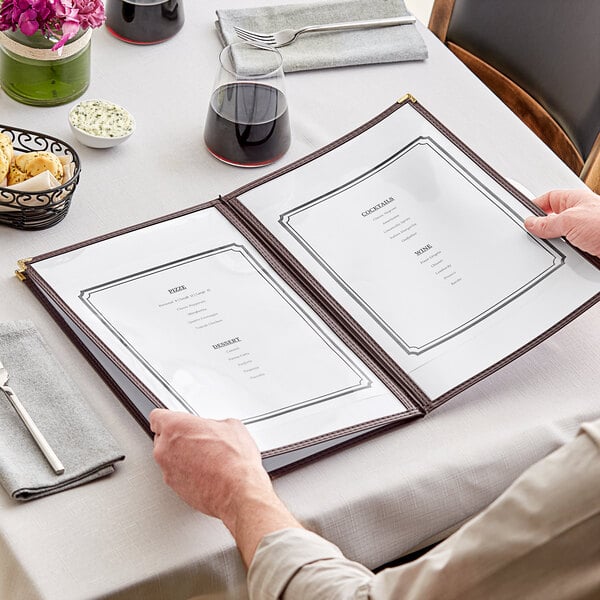 A man holding a brown H. Risch menu cover with gold corners at a table in a fine dining restaurant.