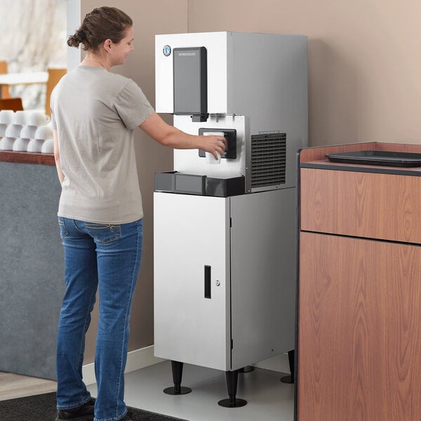 A woman using a Hoshizaki cubelet ice maker and water dispenser.